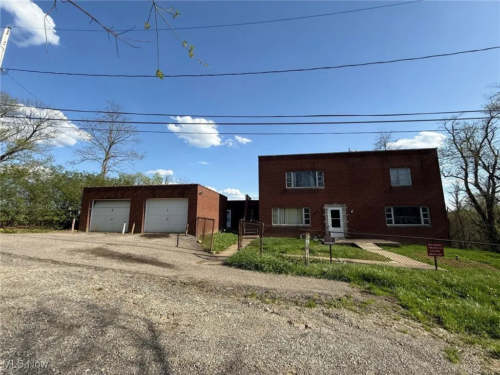 View of front facade with a garage, brick siding, and fence