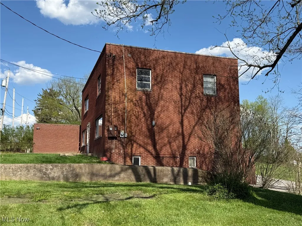 View of property exterior featuring a yard and brick siding