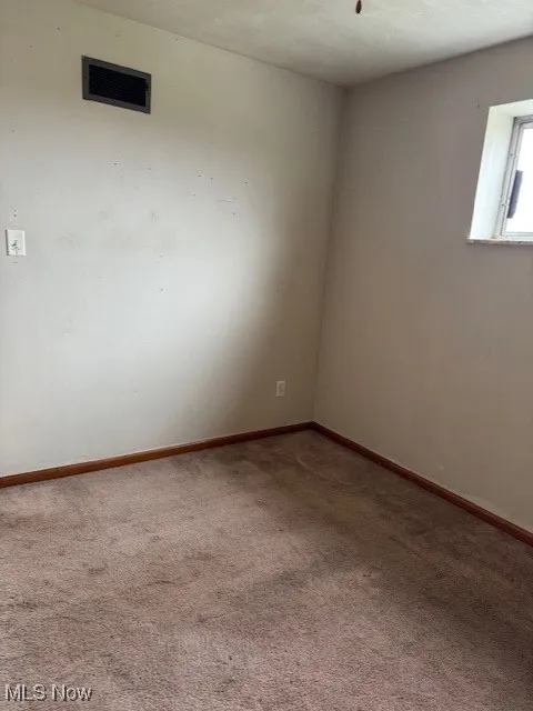 Carpeted spare room with baseboards and visible vents