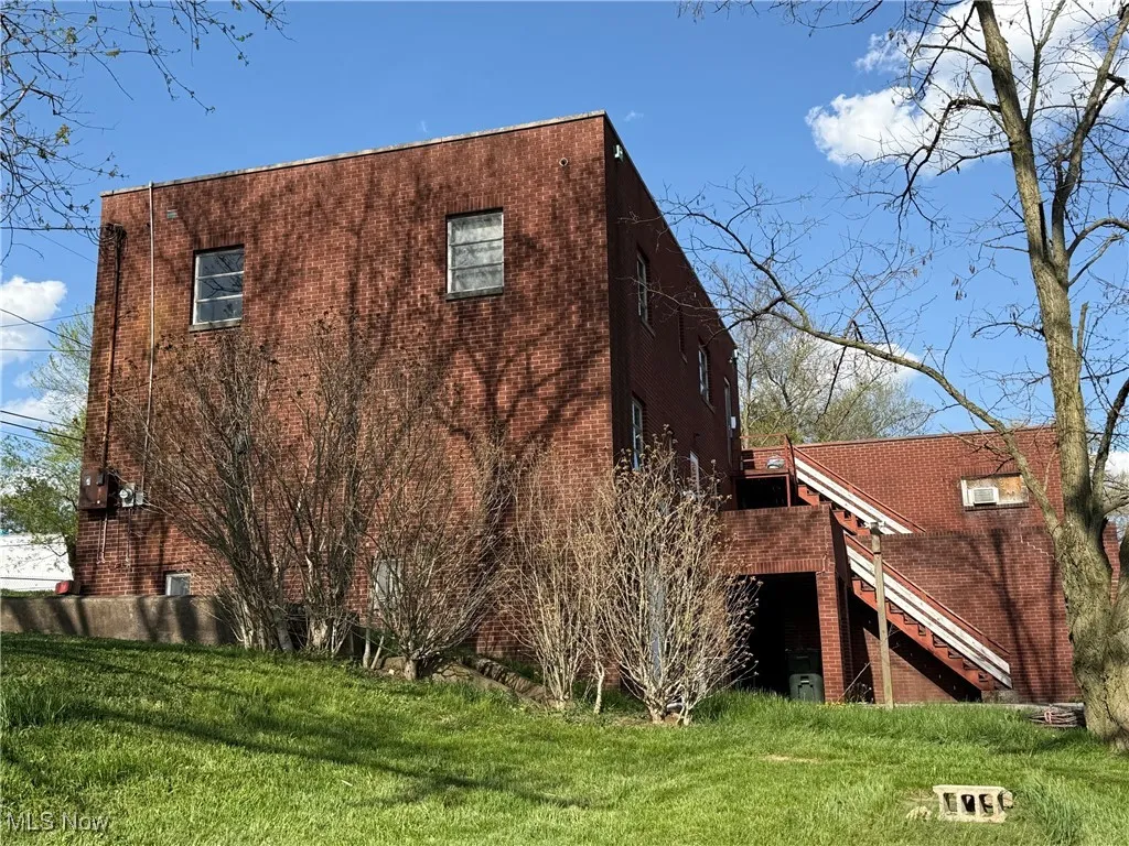 View of home's exterior with a deck, stairs, a yard, and brick siding