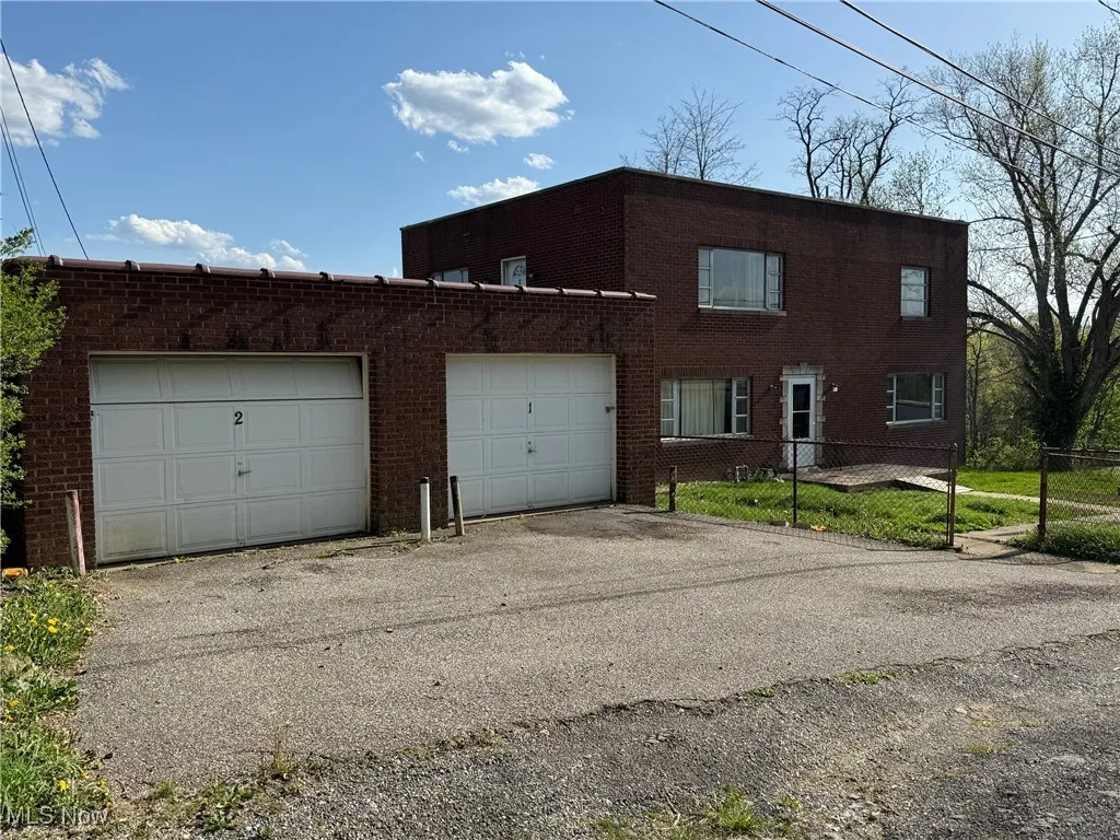 View of front of home featuring brick siding, fence, and driveway