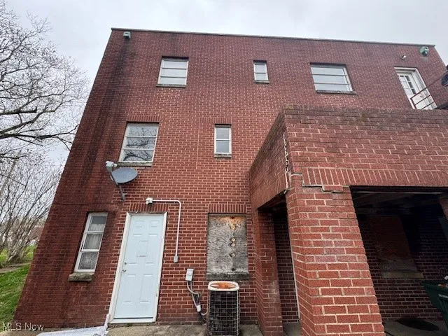 View of back of home featuring brick siding and central AC