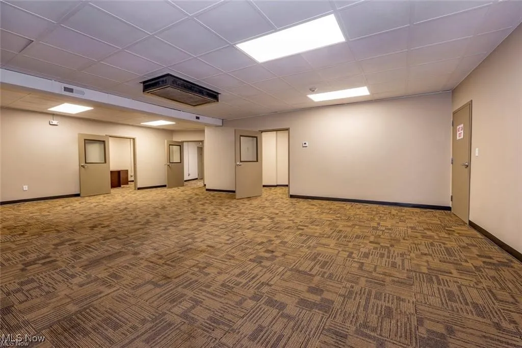 Empty room with carpet, baseboards, and a drop ceiling