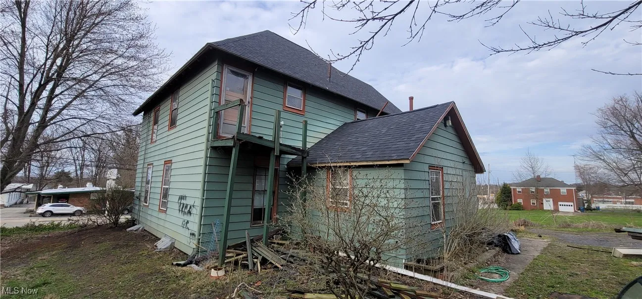 View of home's exterior featuring a shingled roof and an outdoor structure