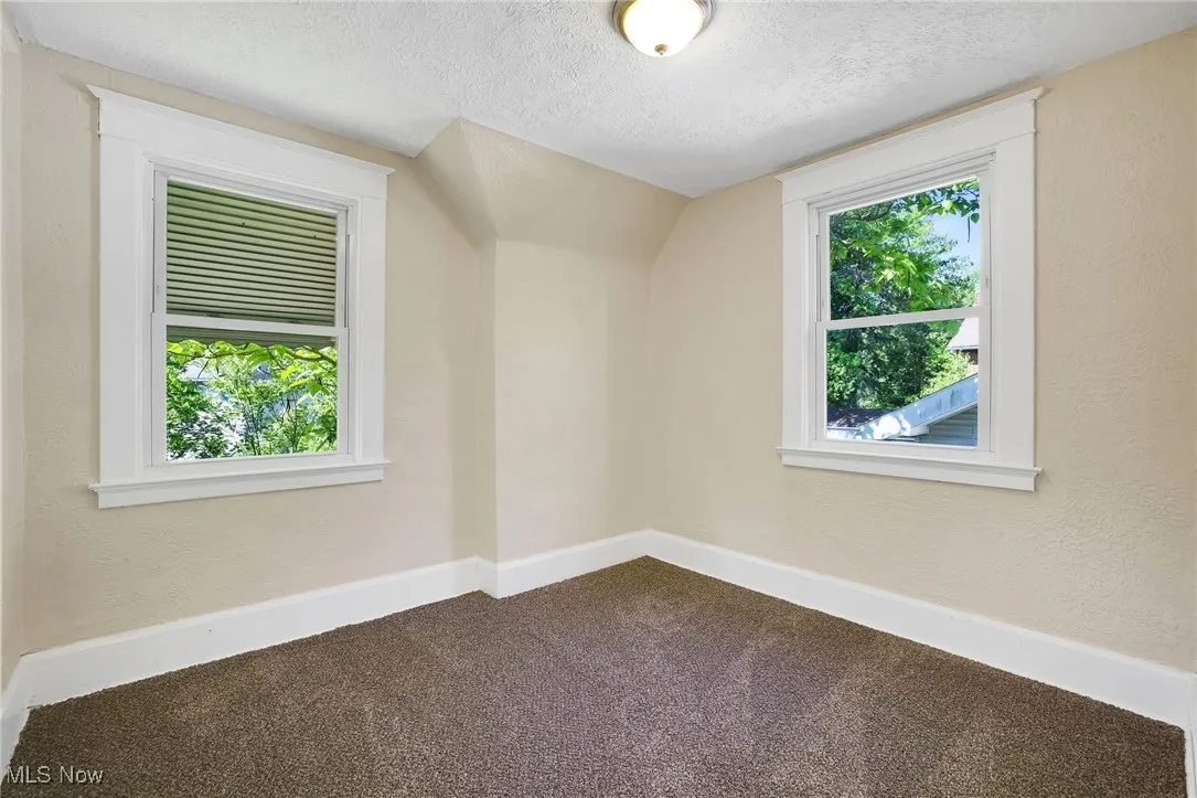 Bonus room featuring a textured ceiling, dark colored carpet, and baseboards