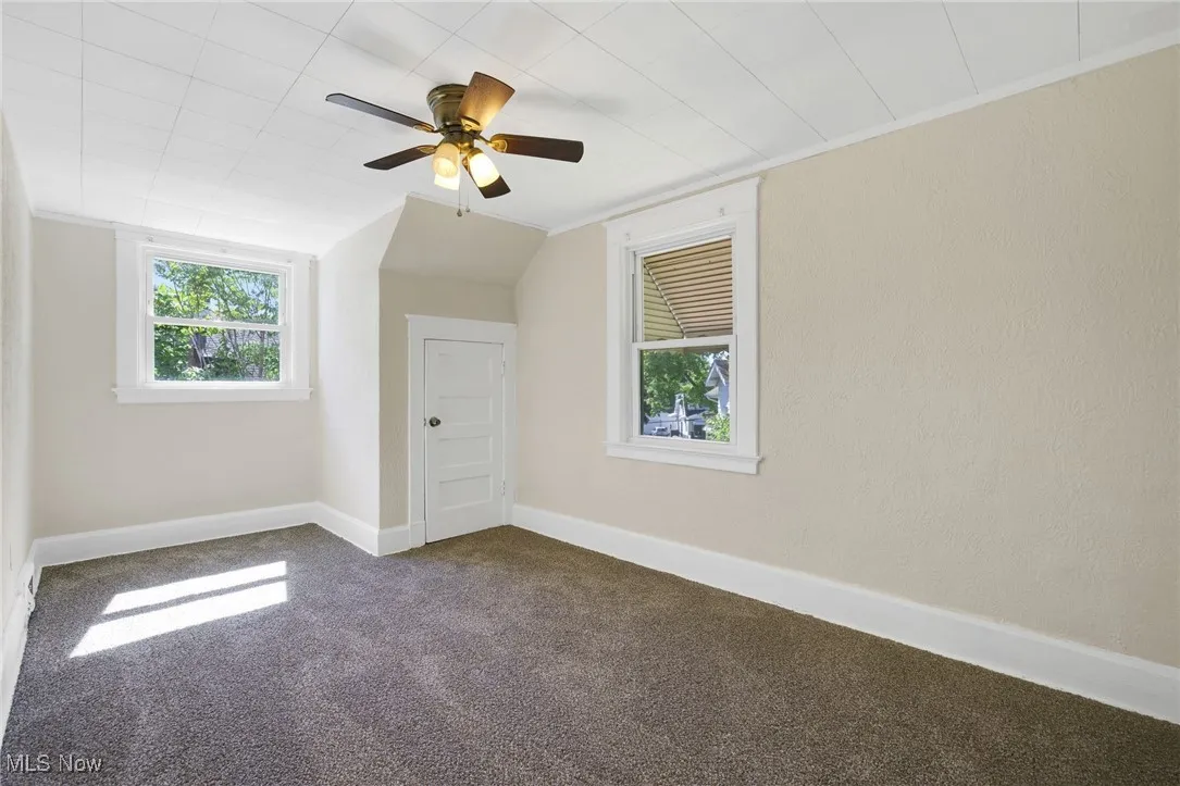 Bonus room featuring dark carpet, ceiling fan, baseboards, and vaulted ceiling
