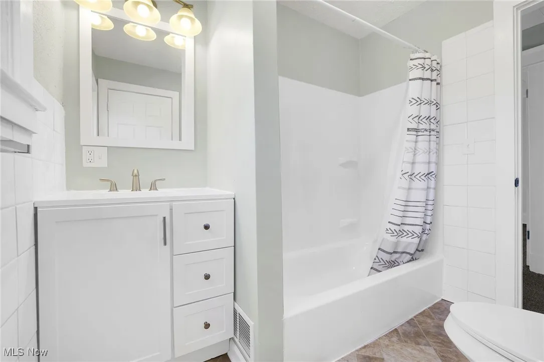 Bathroom with vanity, toilet, and shower / bath combo with shower curtain