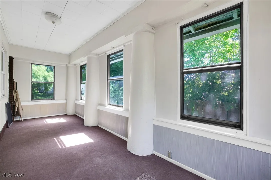 Unfurnished sunroom featuring carpet flooring, a wainscoted wall, and wood walls