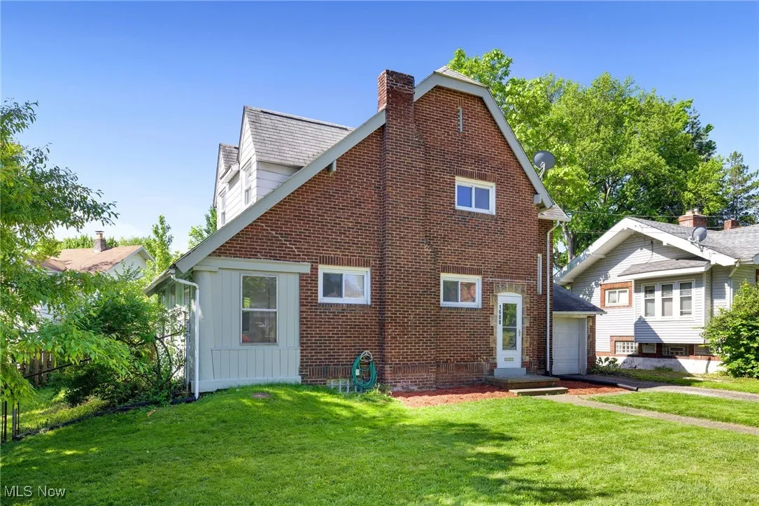 View of property exterior featuring board and batten siding, a chimney, a lawn, and a garage