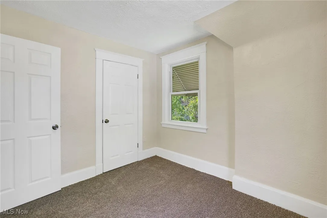 Bonus room featuring dark colored carpet, a textured ceiling, and baseboards