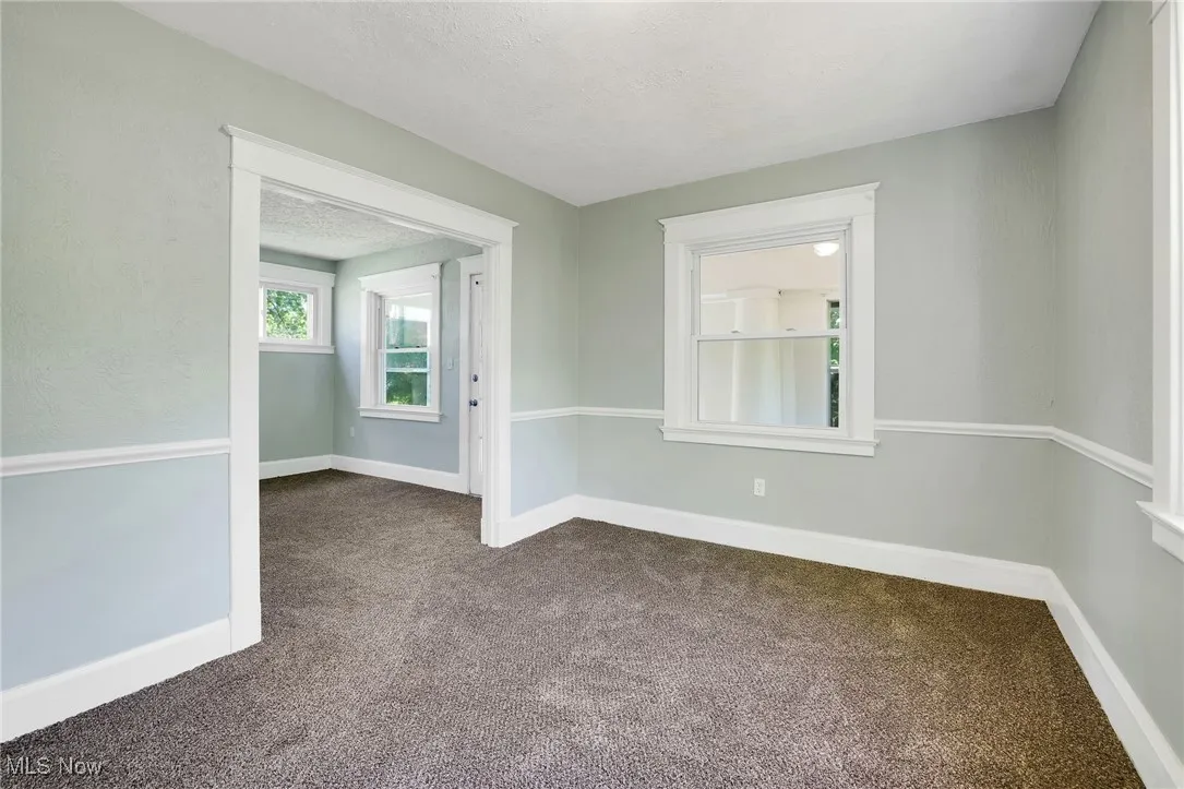 Spare room featuring dark colored carpet, baseboards, and a textured ceiling
