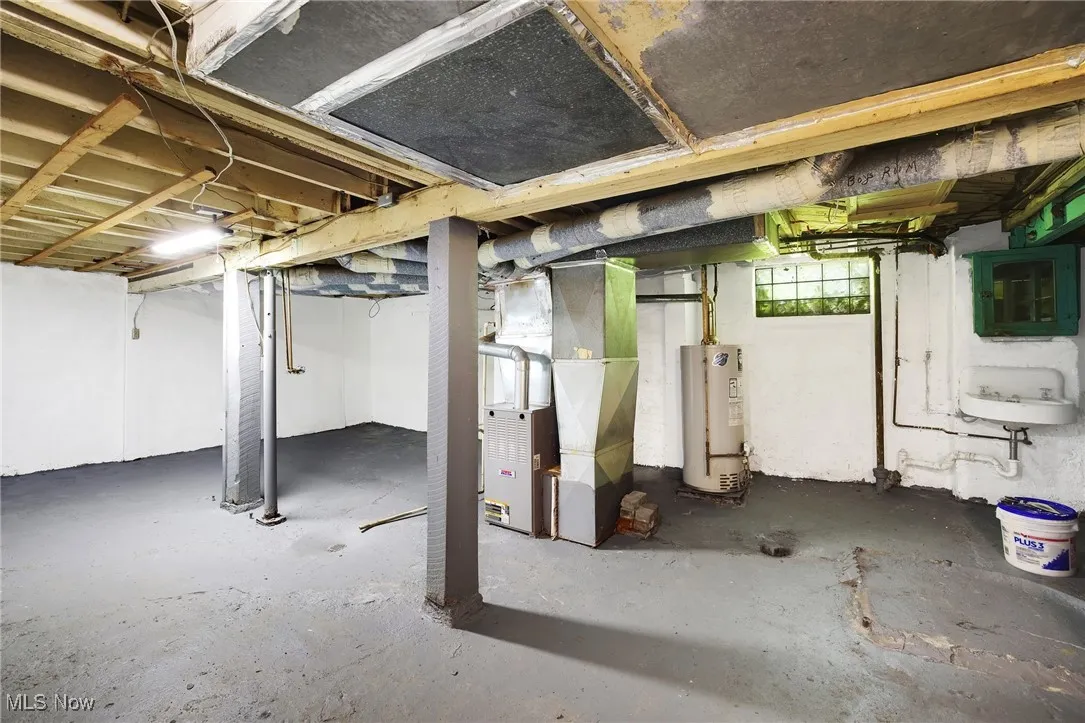 Below grade area with water heater, heating unit, and a sink