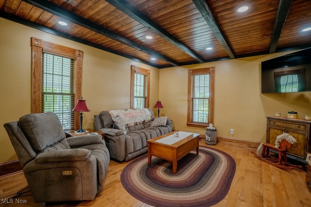 Living area featuring wood ceiling with exposed beams, hardwood / wood-style floors, and baseboards