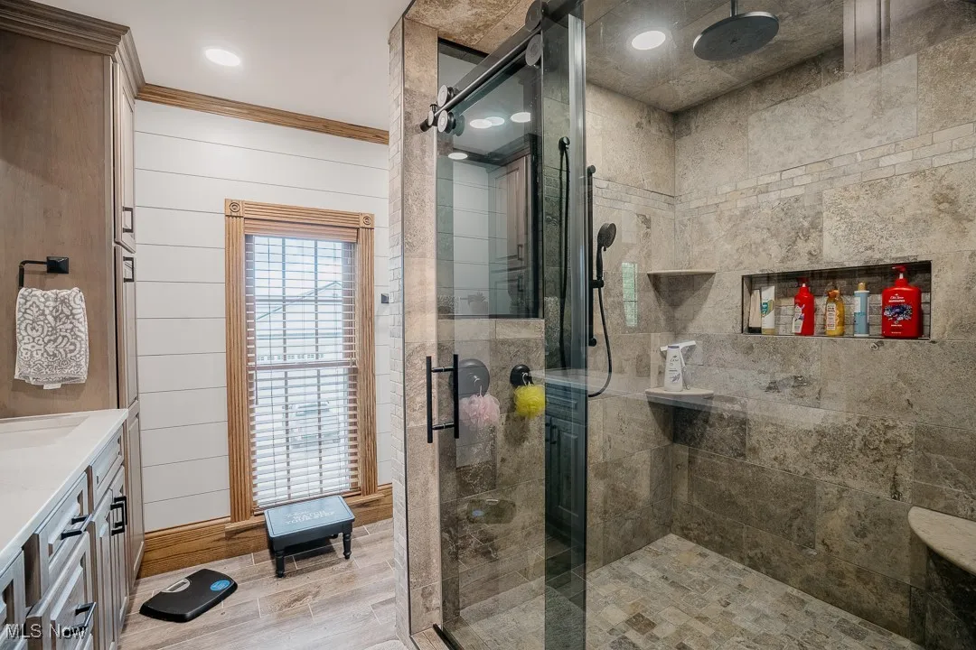 Bathroom with a stall shower, wood finished floors, vanity, and crown molding