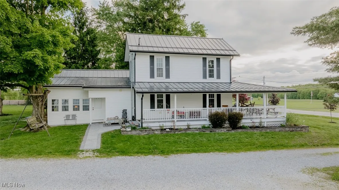 Country-style home featuring a porch, a standing seam roof, metal roof, and a front yard