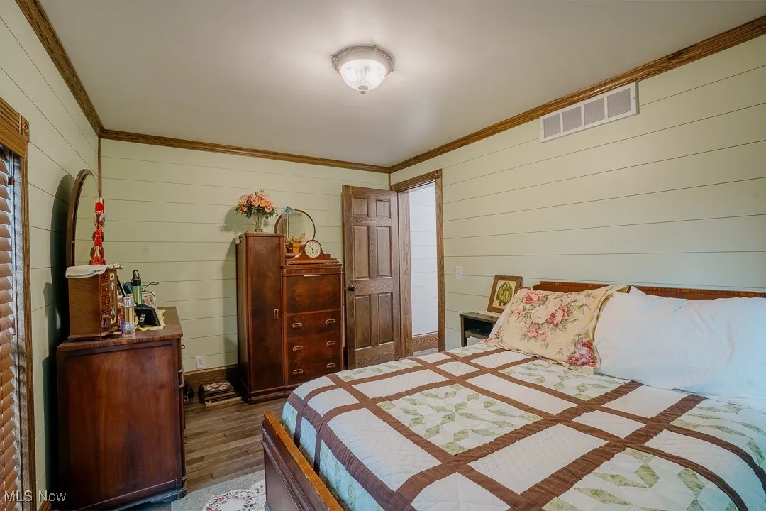 Bedroom featuring crown molding, wood finished floors, and wooden walls
