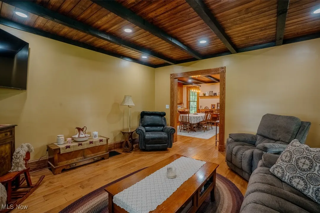 Living area featuring wooden ceiling with exposed beams, wood-type flooring, baseboards, and recessed lighting