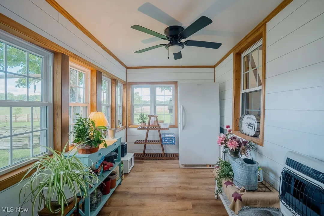 Sunroom / solarium featuring heating unit, wood finished floors, plenty of natural light, and crown molding