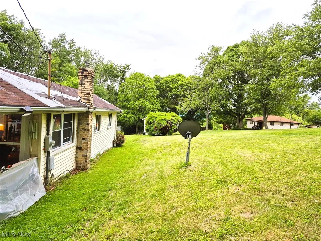 View of green lawn featuring view of scattered trees