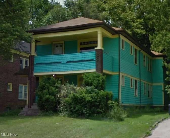 View of front of house featuring a balcony and a front lawn
