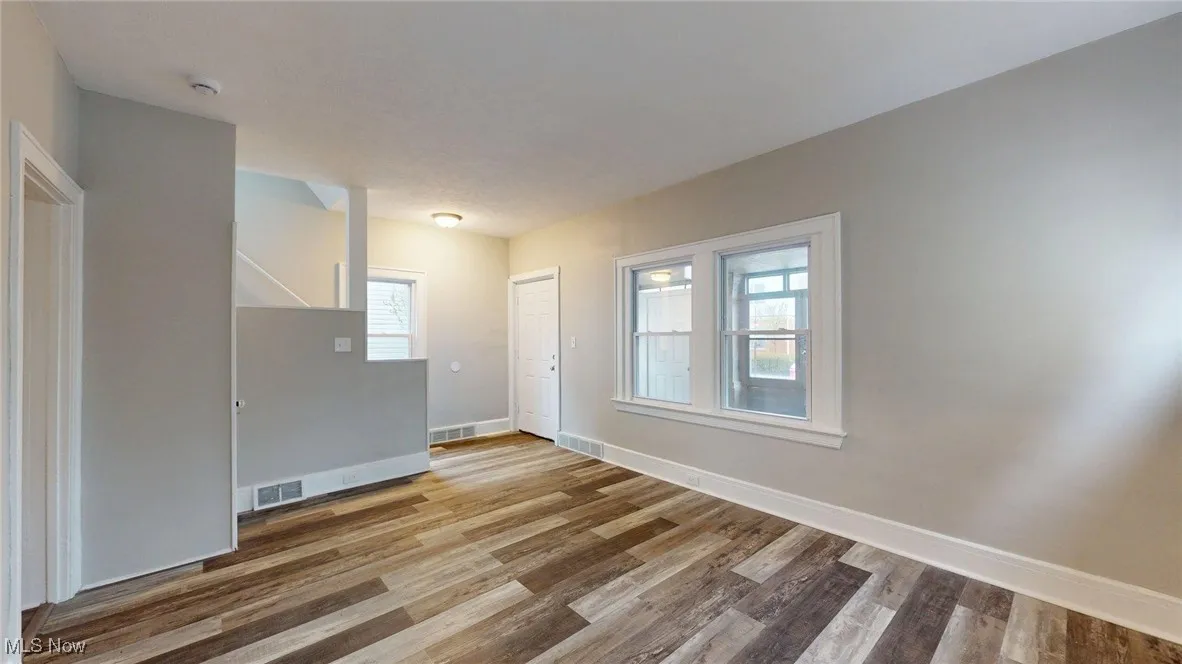 Empty room featuring baseboards, wood finished floors, and visible vents