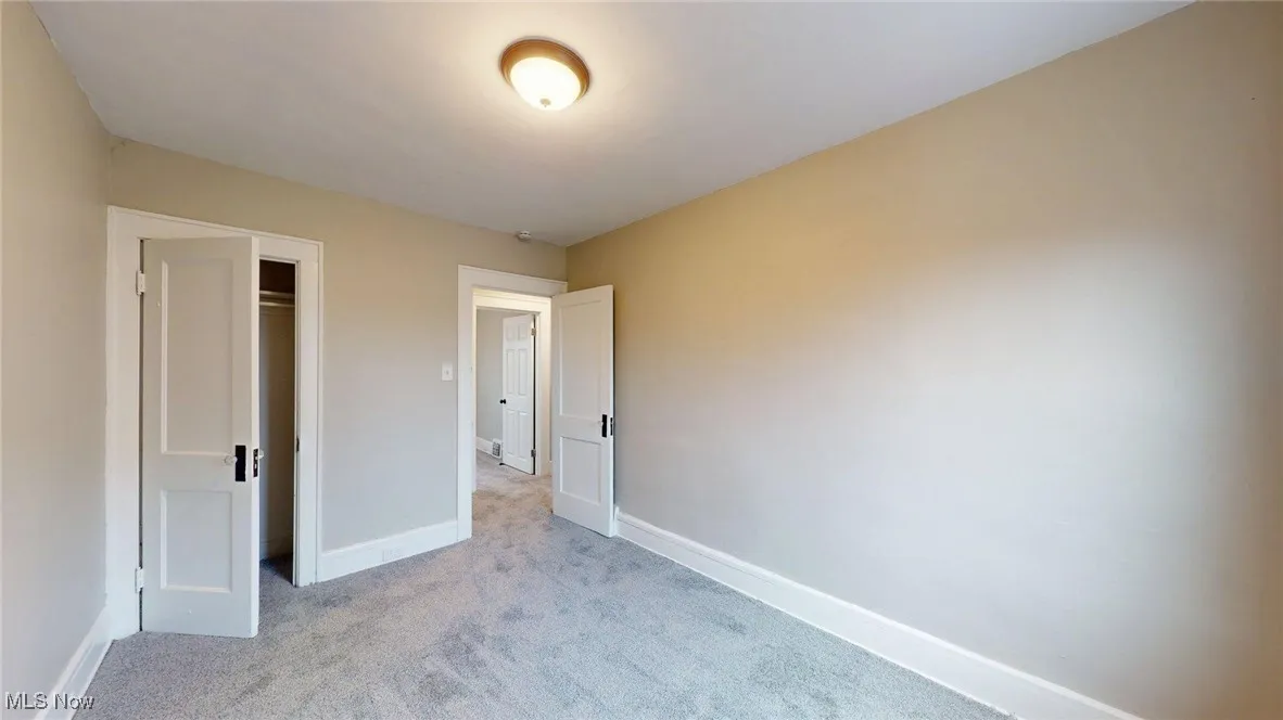 Unfurnished bedroom featuring baseboards, a closet, and light colored carpet