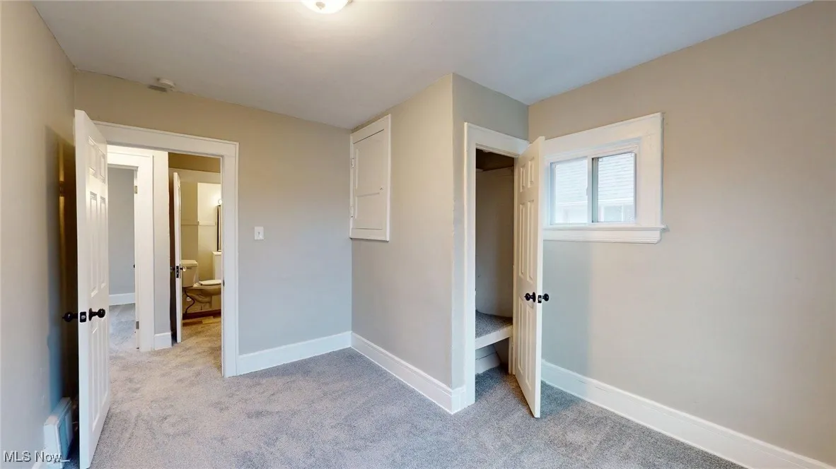 Unfurnished bedroom with baseboards and light colored carpet