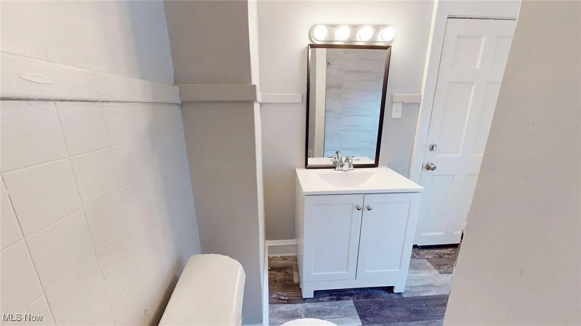 Bathroom with vanity, wood finished floors, and tile walls