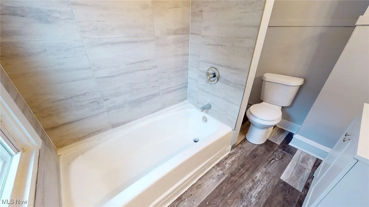 Bathroom featuring toilet, shower / bathtub combination, and wood finished floors