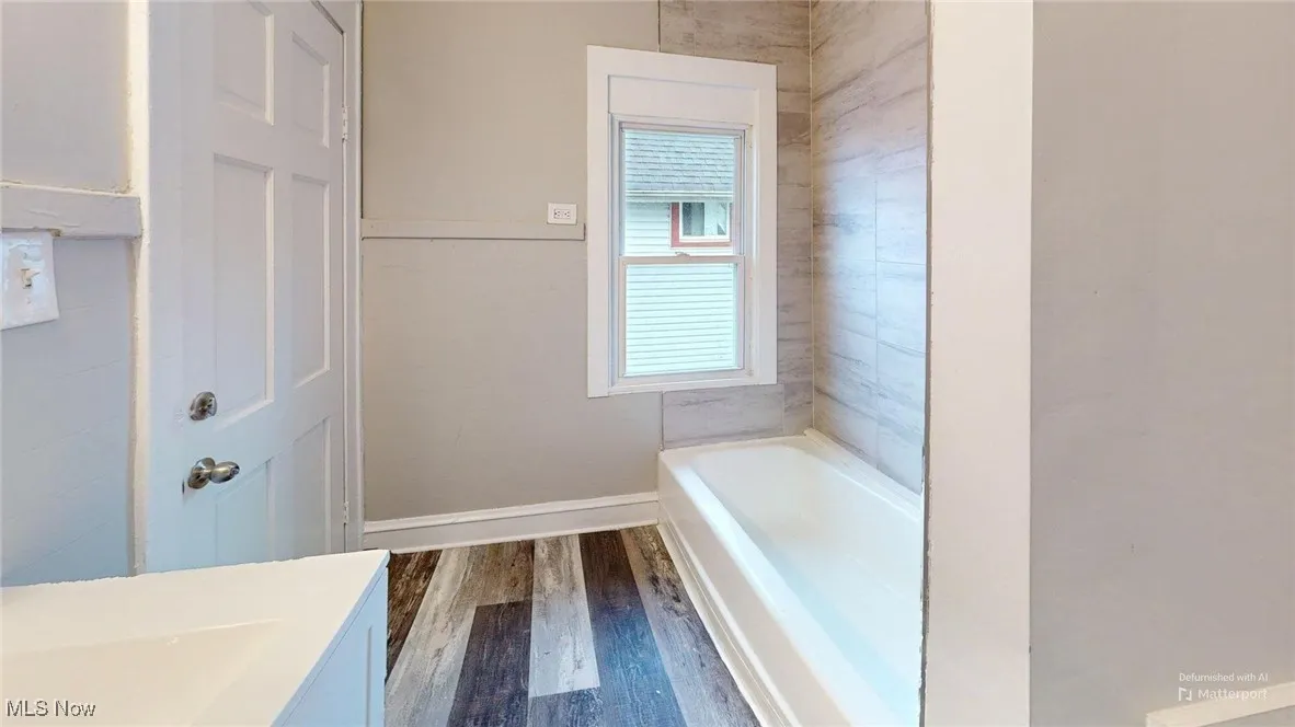 Bathroom with wood finished floors, vanity, a bathing tub, and baseboards