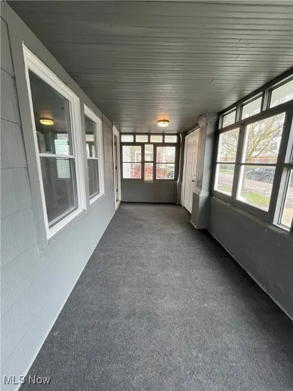 Unfurnished sunroom with a wealth of natural light and carpet