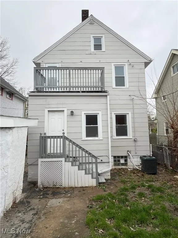Back of property featuring fence, a chimney, a balcony, and central AC unit