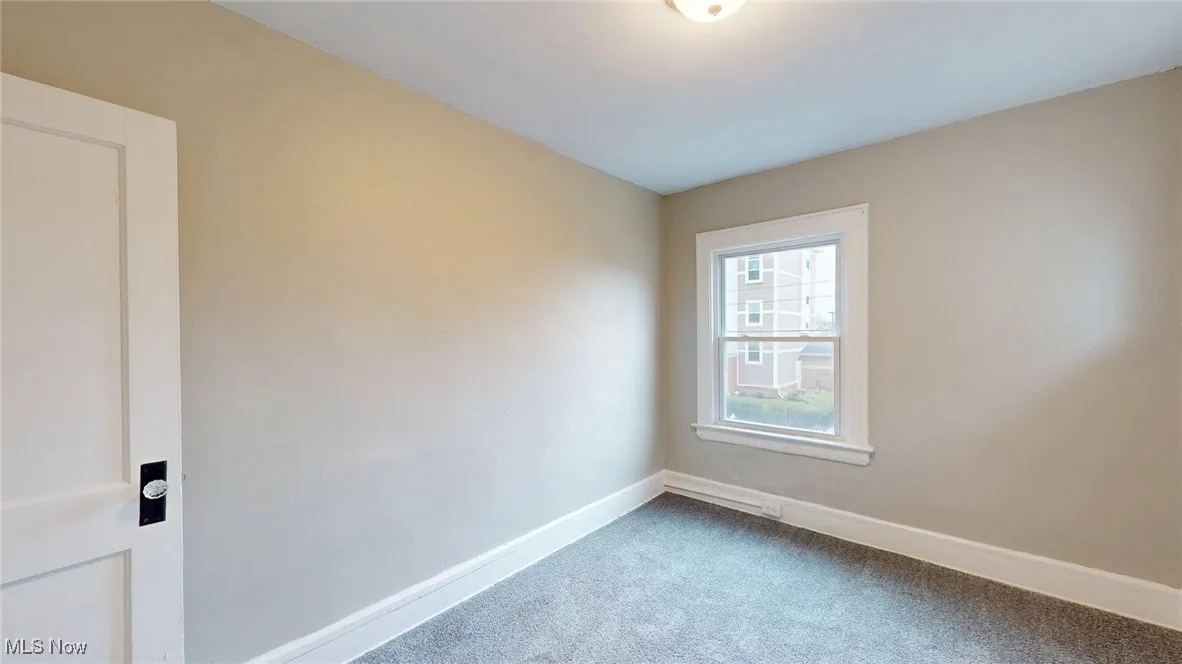 Empty room with dark colored carpet and baseboards