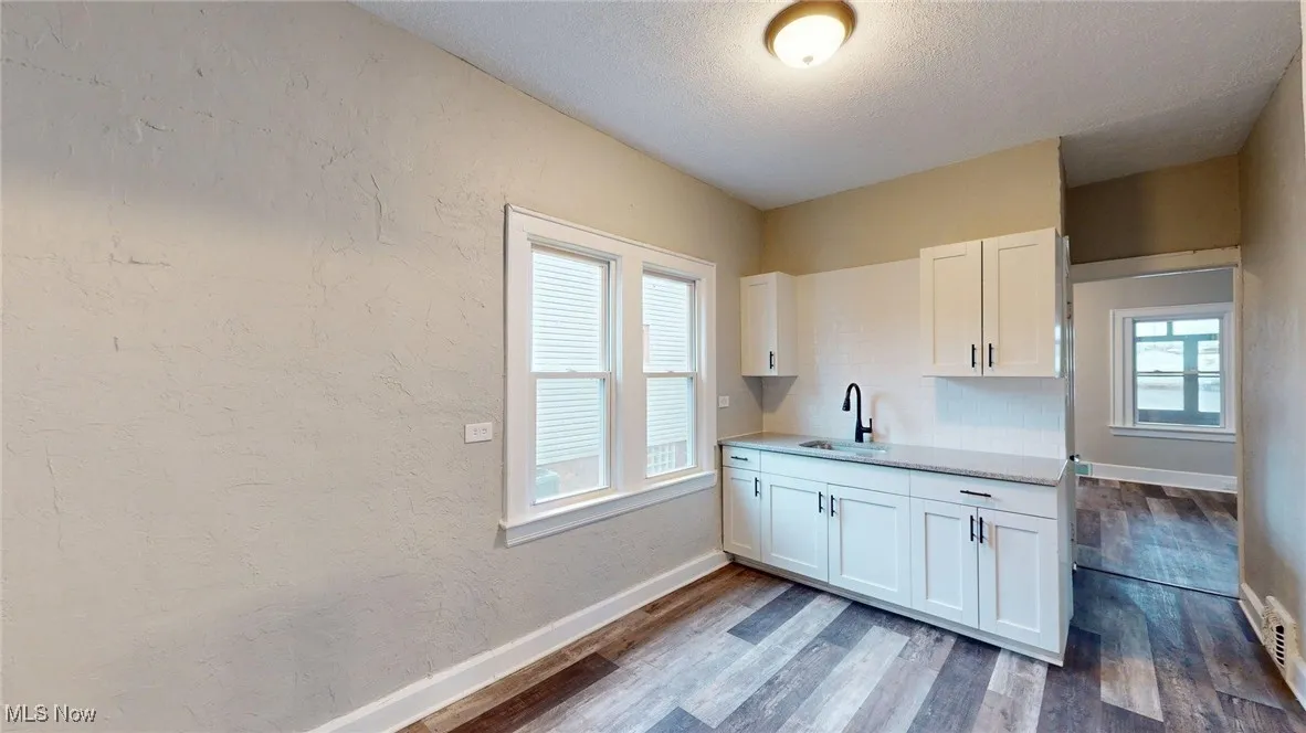 Kitchen featuring white cabinetry, a sink, and dark wood-style floors