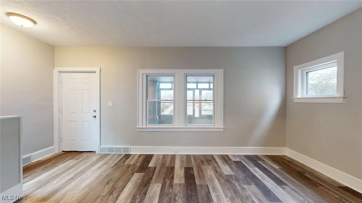 Spare room with wood finished floors, visible vents, and baseboards