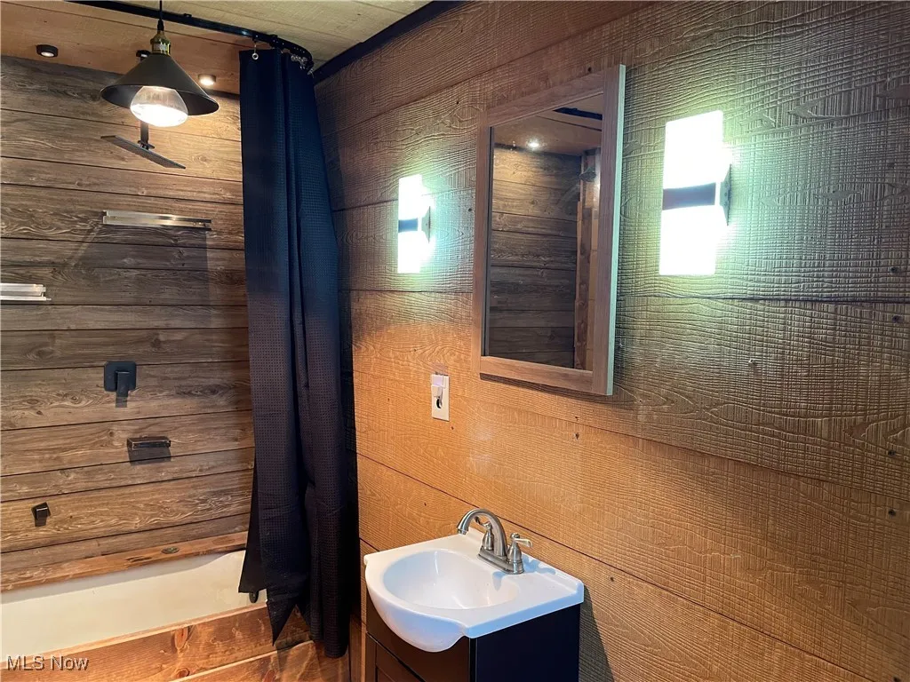 Bathroom featuring wooden walls, vanity, and a shower with shower curtain