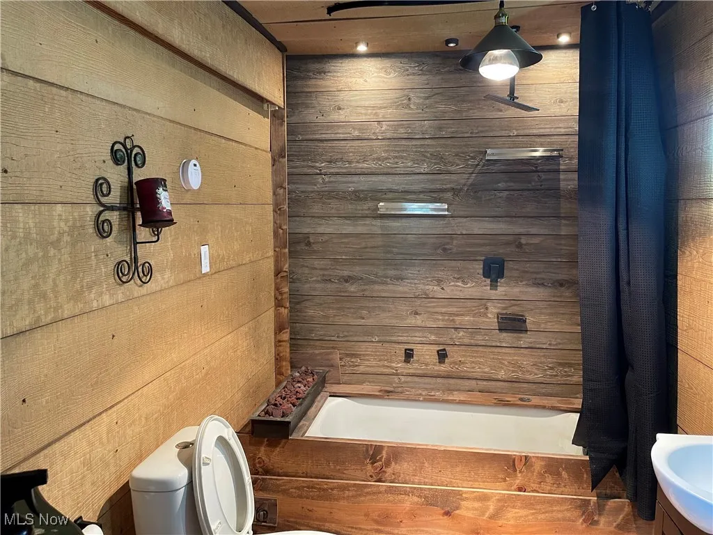 Bathroom featuring wood walls and shower / tub combo with curtain