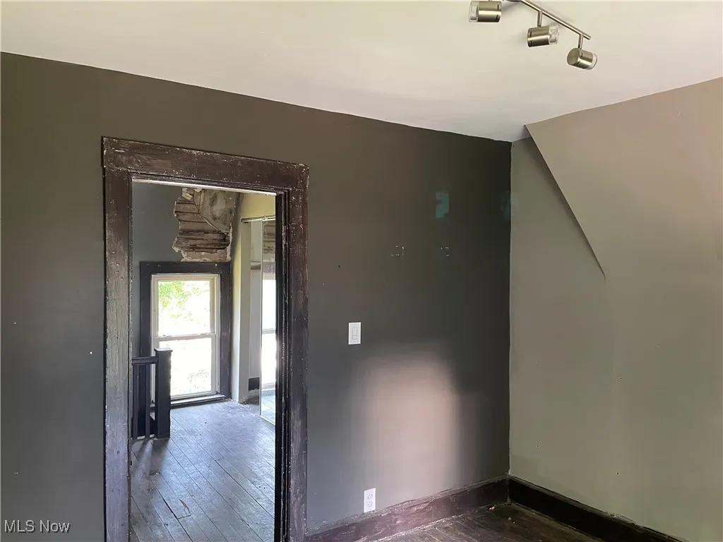 Empty room featuring rail lighting and hardwood / wood-style flooring