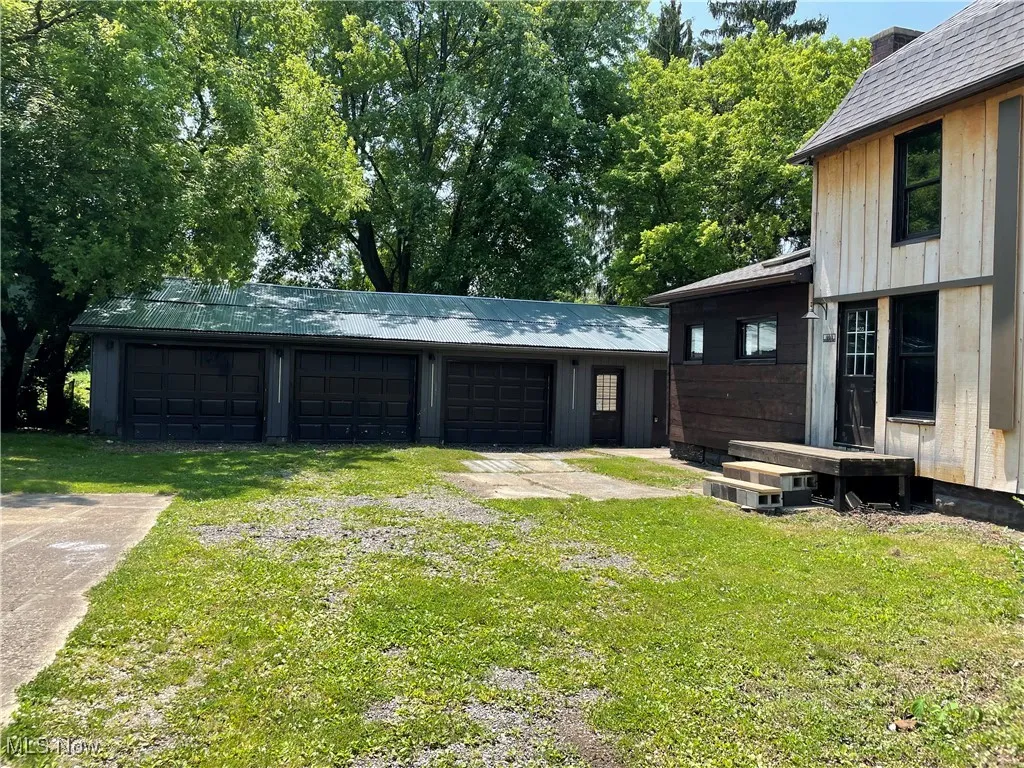 View of grassy yard featuring an outdoor structure, a garage, and driveway