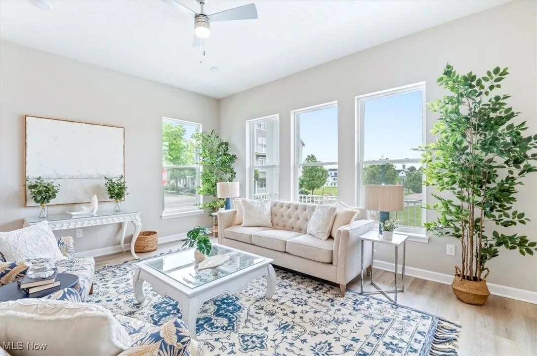 Living area featuring wood finished floors, a ceiling fan, and baseboards