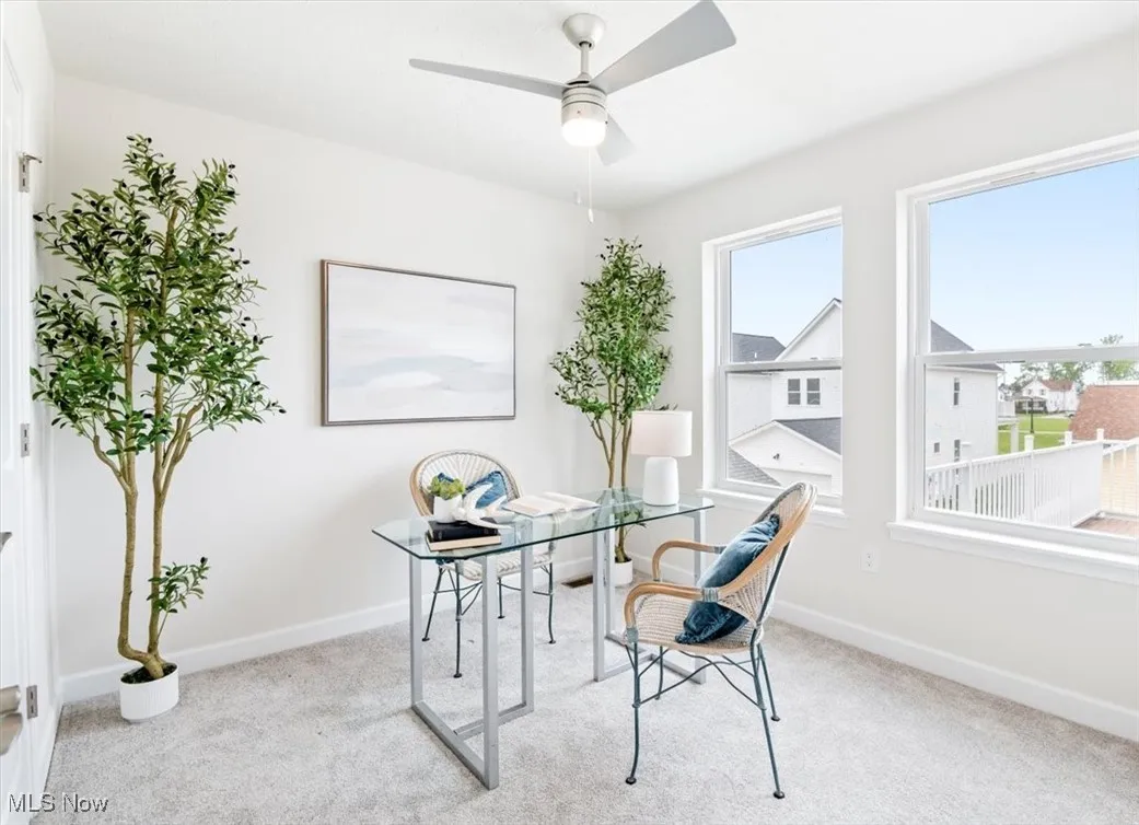 Carpeted office with ceiling fan and baseboards