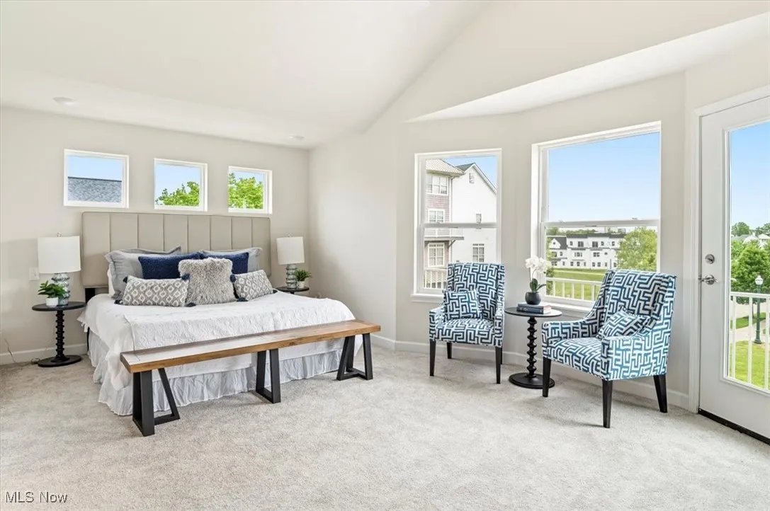 Bedroom with multiple windows, light carpet, vaulted ceiling, baseboards, and access to exterior