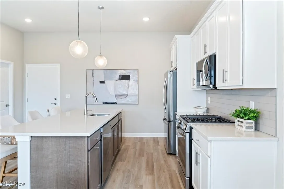 Kitchen featuring a sink, appliances with stainless steel finishes, a kitchen island with sink, a kitchen breakfast bar, and light wood-style floors
