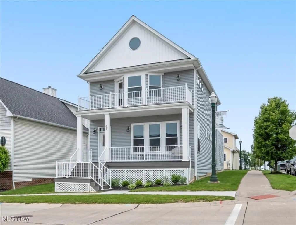 View of front facade featuring a balcony, covered porch, and a front lawn