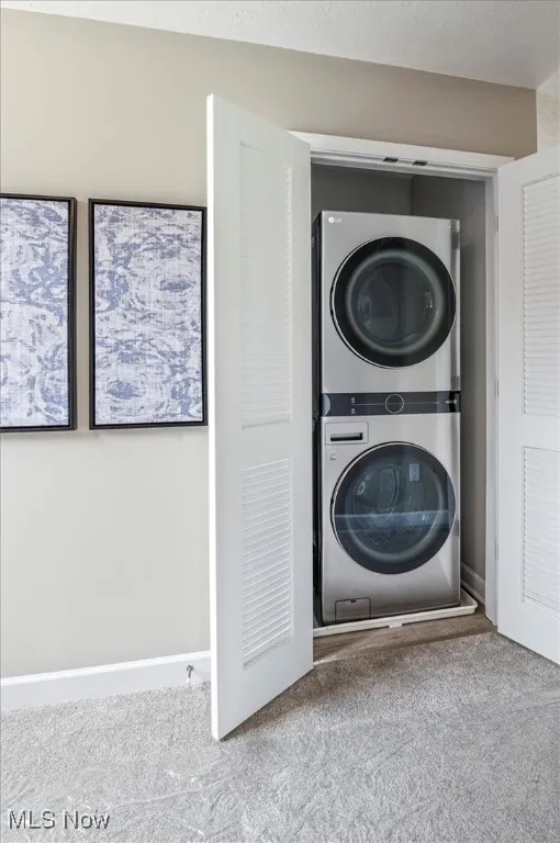 Laundry room with stacked washer / dryer and carpet flooring
