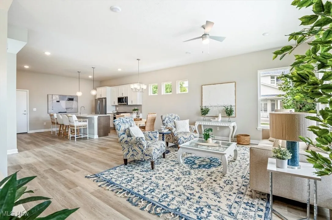 Living area featuring plenty of natural light, a ceiling fan, light wood-style flooring, recessed lighting, and a chandelier