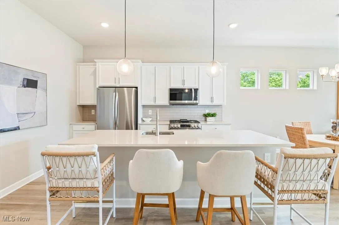 Kitchen featuring appliances with stainless steel finishes, a sink, tasteful backsplash, a kitchen island with sink, and recessed lighting