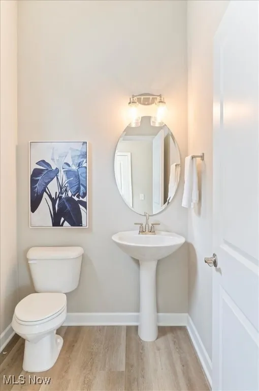 Bathroom with wood finished floors, toilet, and baseboards