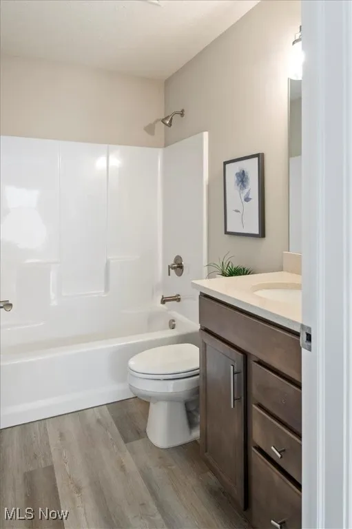 Full bath with vanity, wood finished floors, shower / bath combination, and toilet