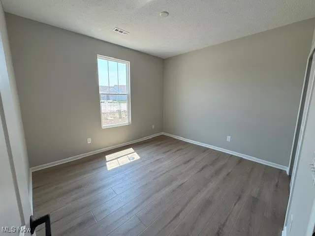 Unfurnished room with a textured ceiling and wood finished floors